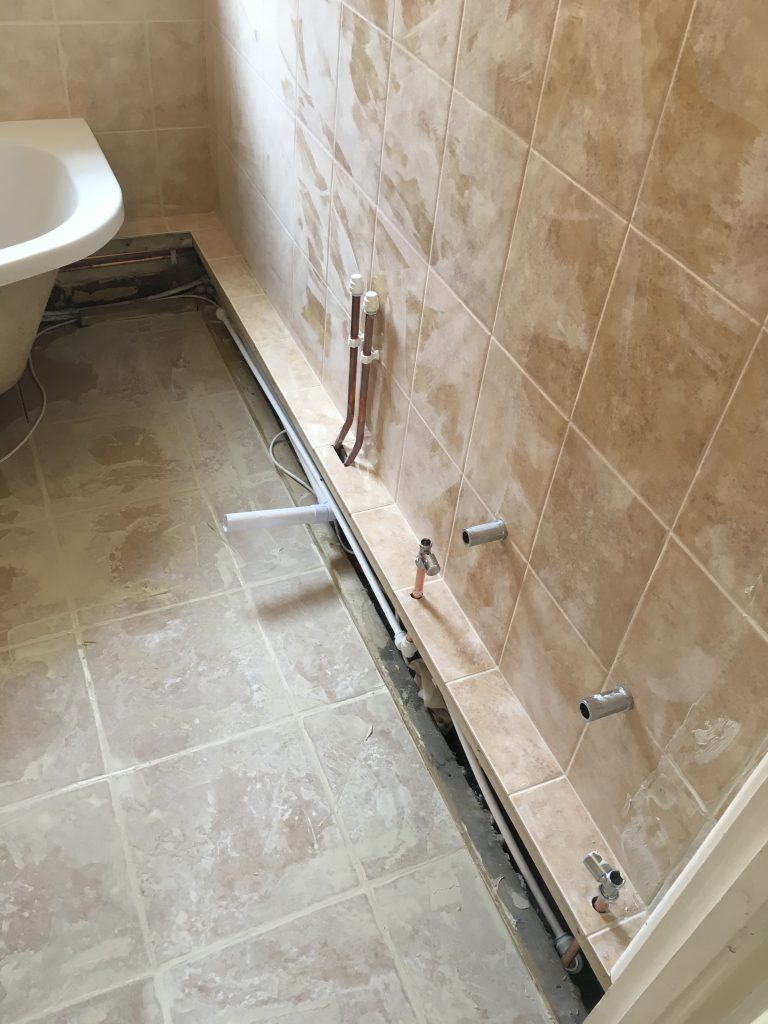 Exposed pipework in clay tiled walls and skirting with new tiled flooring 