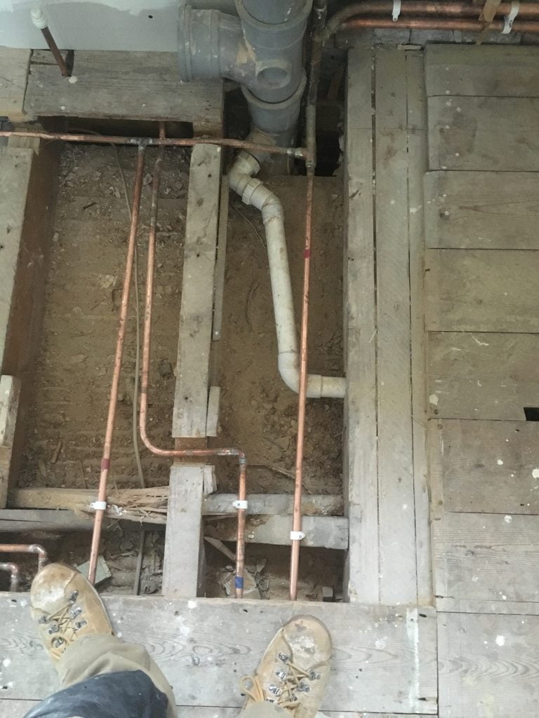 Copper and plastic pipework under old wooden bathroom floor in a bathroom remodel in Teignmouth