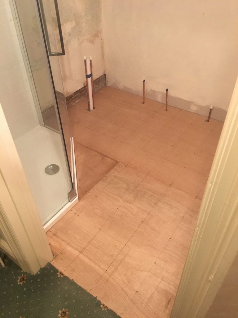Copper pipework coming through old vinyl bathroom flooring in a bathroom remodel in Teignmouth