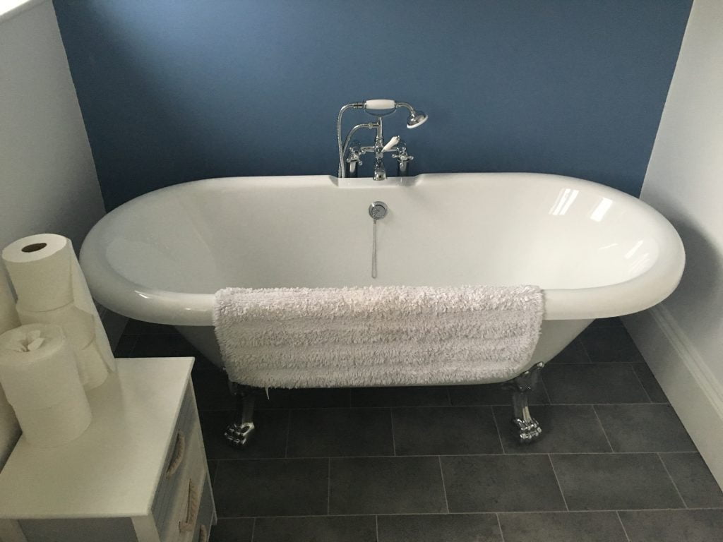 White bath with chrome feet and taps set against a blue feature wall for a bathroom remodel in Teignmouth