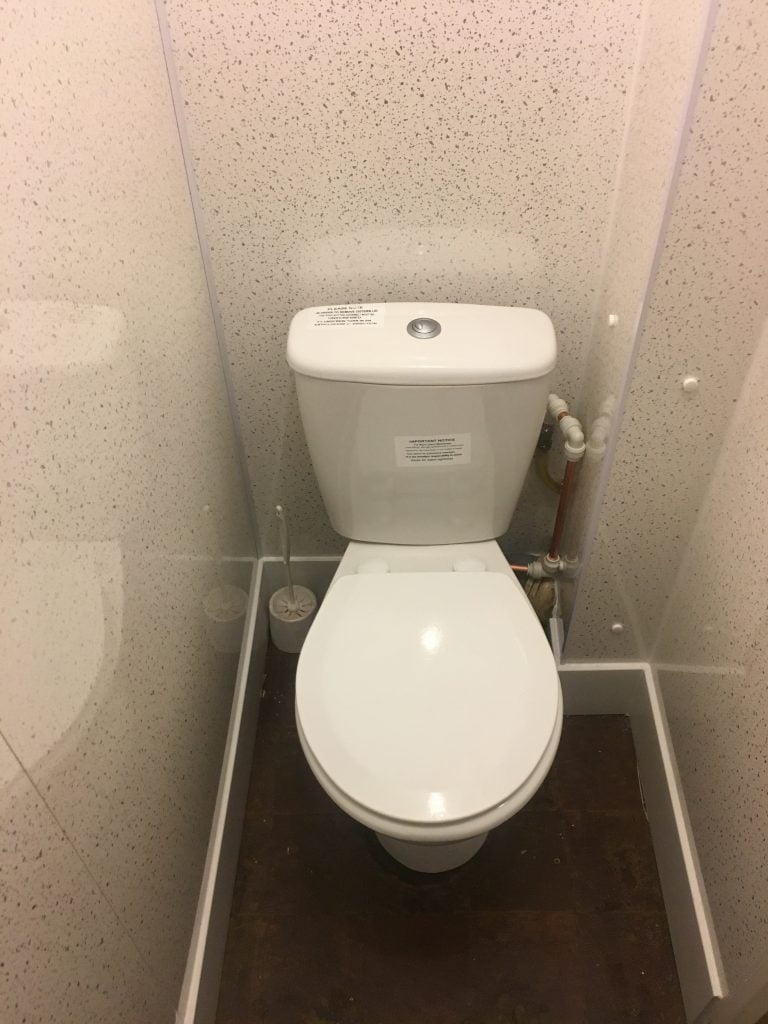 Toilet cubicle with white toilet and speckled wipeable walls